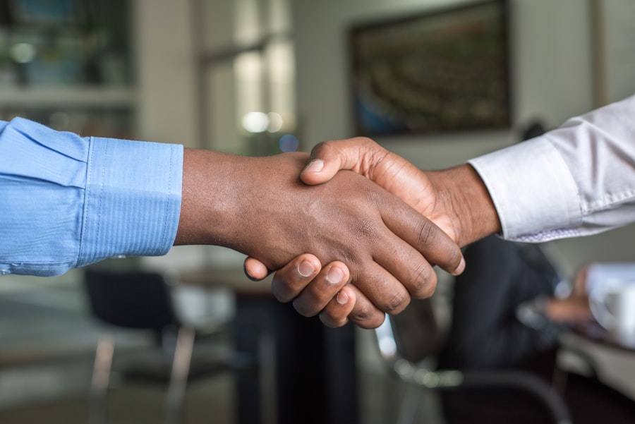 Two partners shaking hands over a desk